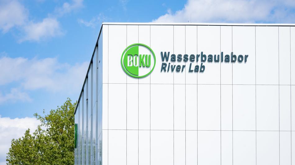 Fassadenansicht mit der Aufschrift „BOKU Wasserbaulabor River Lab“ an einem modernen Institutsgebäude