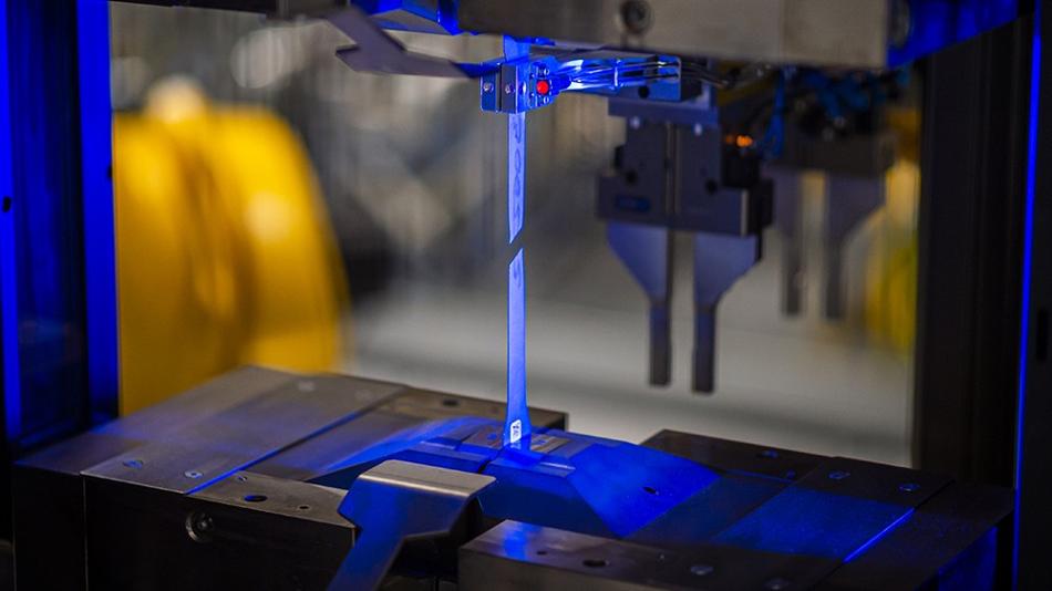 Nahaufnahme einer Stahlprobe während des Zugversuchs unter blauem Licht.