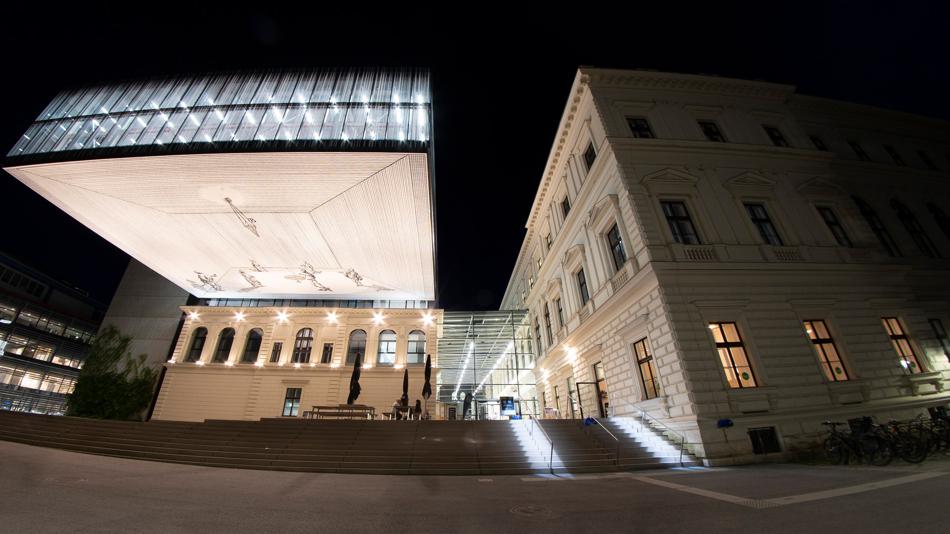 Blick durch ein Fischauge auf die Universitätsbilbiothek und das Hauptgebäude der Universität Graz bei Nacht