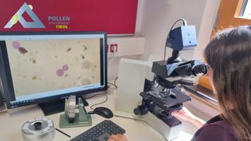 Mitarbeiterin des Pollenwarndienstes vor Mikroskop und Bildschirm