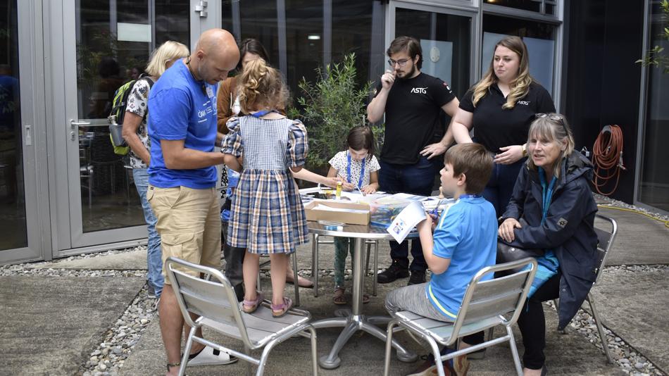 Kinder und erwachsene Helfer beim Basteln von Papierraketen