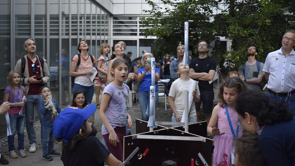 Kinder und Erwachsene beobachten den Start der Papierraketen