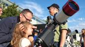 große und kleine Besucher:innen werfen einen Blick durch Teleskope