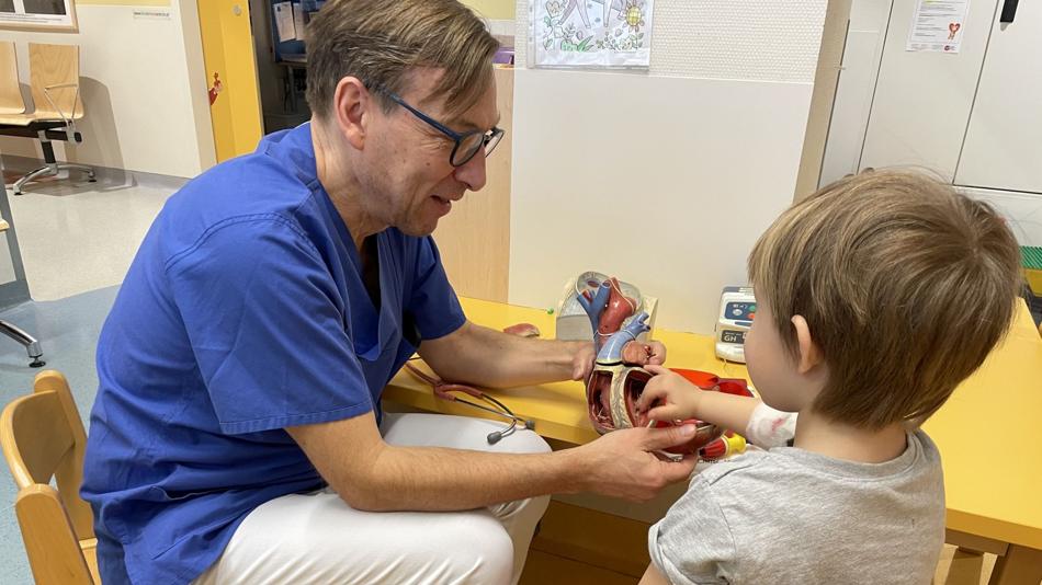 Arzt erklärt einem Kind spielerisch die Funktion des Herzens