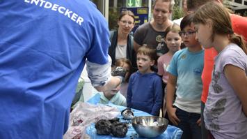 Kinder und Erwachsene betrachten einen frisch zubereiteten "Kometen"