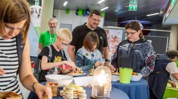 Das Bild zeigt Besucher:innen der Langen Nacht der Forschung an der FH JOANNEUM beim Lösen des Rätselns „Türme von Hanoi“