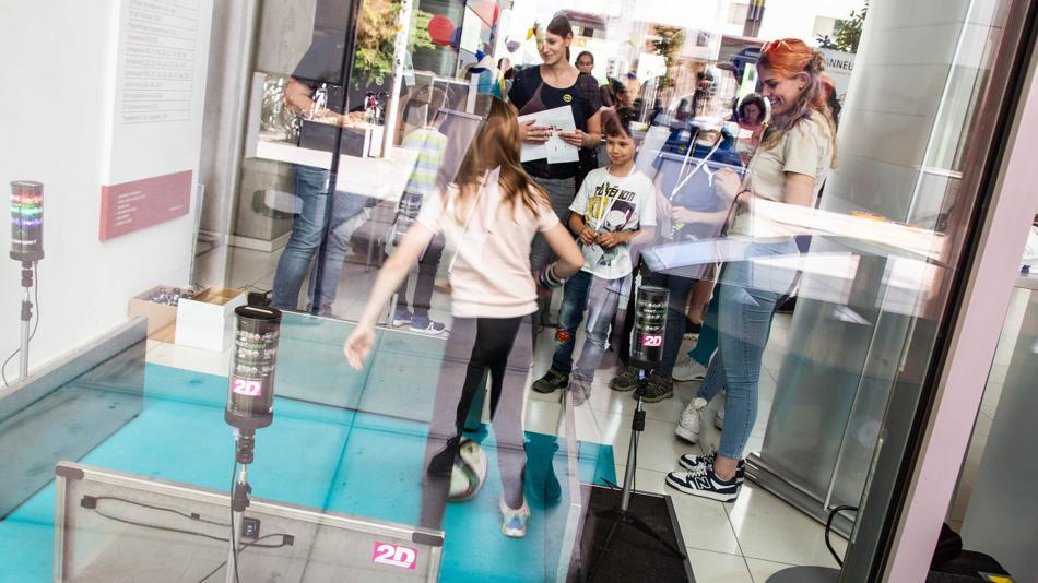 Das Bild zeigt Besucher:innen beim Erproben des Fußball-Testsystem der FH JOANNEUM