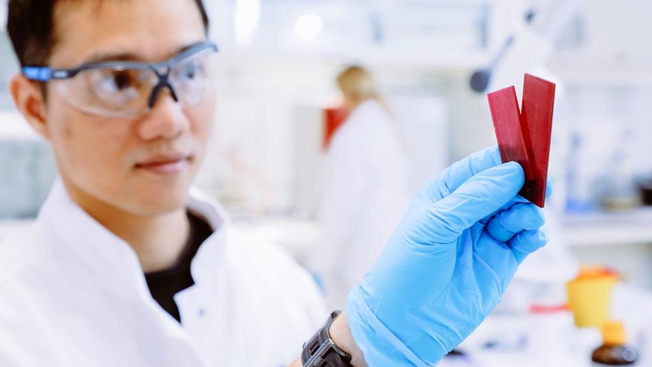 Ein Forscher überprüft den Farbwechsel eines Kunststoffs, um eine gefährliche Temperaturentwicklung frühzeitig zu erkennen.