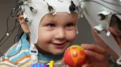 Baby mit EEG-Haube und Spielzeug