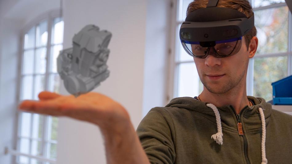 Mann mit VR-Brille hält virtuelles Objekt in der Hand