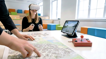 Hände, die auf Karte zeigen, iPad, und Person mit VR-Headset