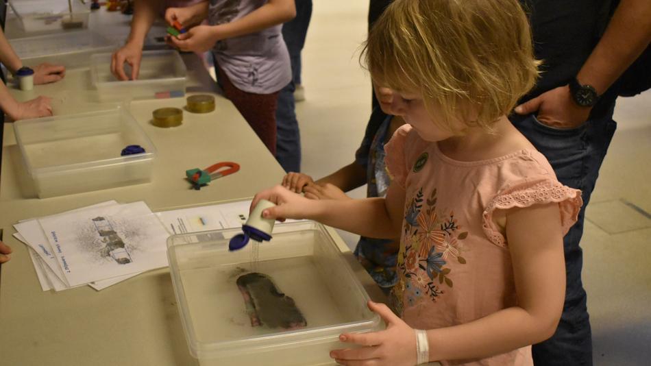 ein kleines Mädchen experimentiert mit Eisenspänen