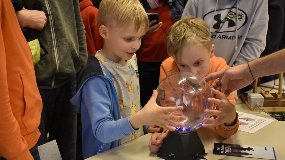 zwei Buben experimentieren mit einer Plasmakugel