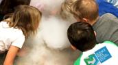 Kinder vor einer rauchenden Schale mit Trockeneis