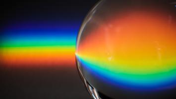 Lichtstrahl in Spektralfarben und Kugel, die in diesen Farben leuchtet