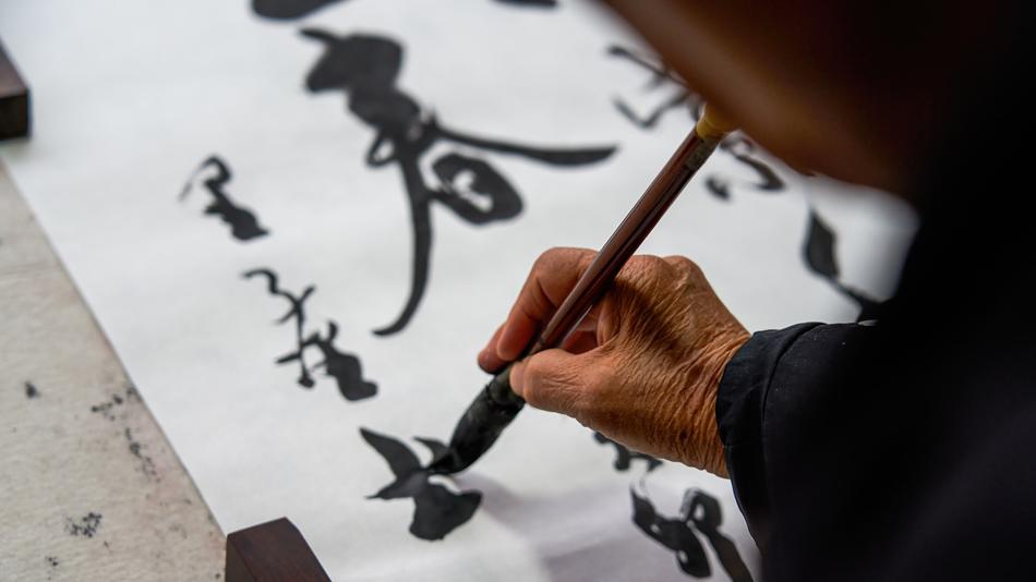 Eine Person aus China malt mit einem Pinsel Schriftzeichen