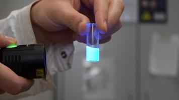UV Licht bringt Flüssigkeit im Labor Glas zum Leuchten