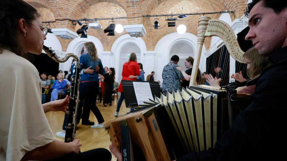 Zwei Musiker*innen, im Bildhintergrund wird getanzt