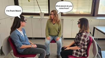 Drei Personen im Gespräch auf Stühlen sitzend mit Eye-Tracking-Brillen