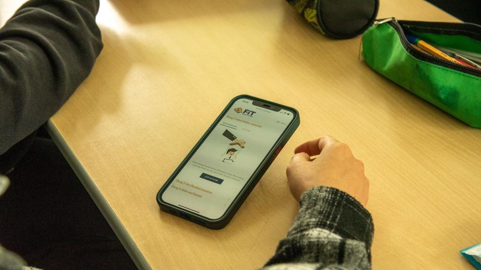 Hände, Federpenal und Handy