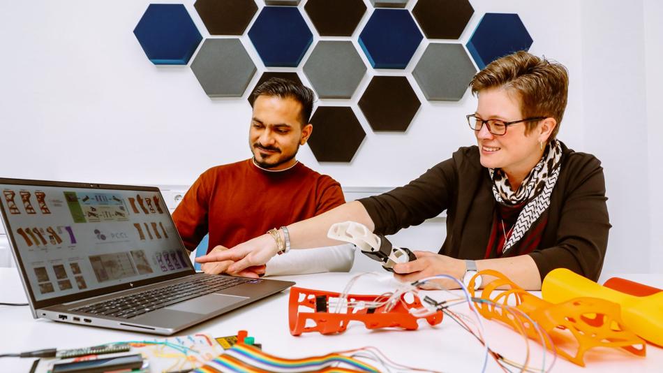 Zwei Forschende diskutieren die Ergebnisse der Optimierung einer medizinischen Stützschiene.