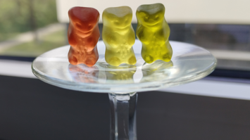 Drei Gummibärchen auf einem umgedrehten Weinglas