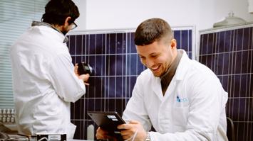 In this laboratory setting, two researchers are conducting near-infrared (NIR) measurements on a photovoltaic (PV) module. One researcher is using a tablet to monitor and record data, while the other operates a device to perform precise NIR analysis, high