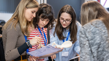 4 weibliche Jugendliche beugen sich konzentriert über ein Blatt Papier