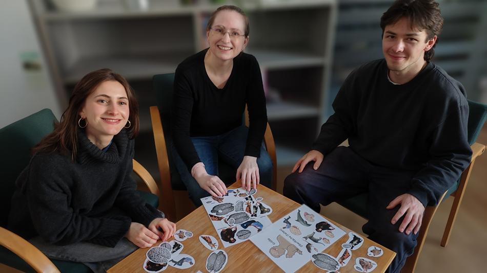 Drei Personen spielen ein Zuordnungsspiel: Sie ordnen Tieren die passenden Gehirne zu.