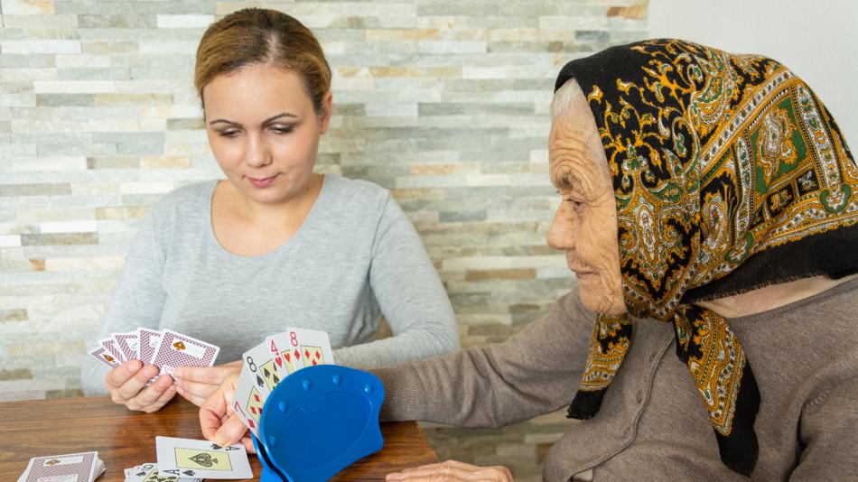Eine Erwachsene und eine Seniorin spielen Karten.