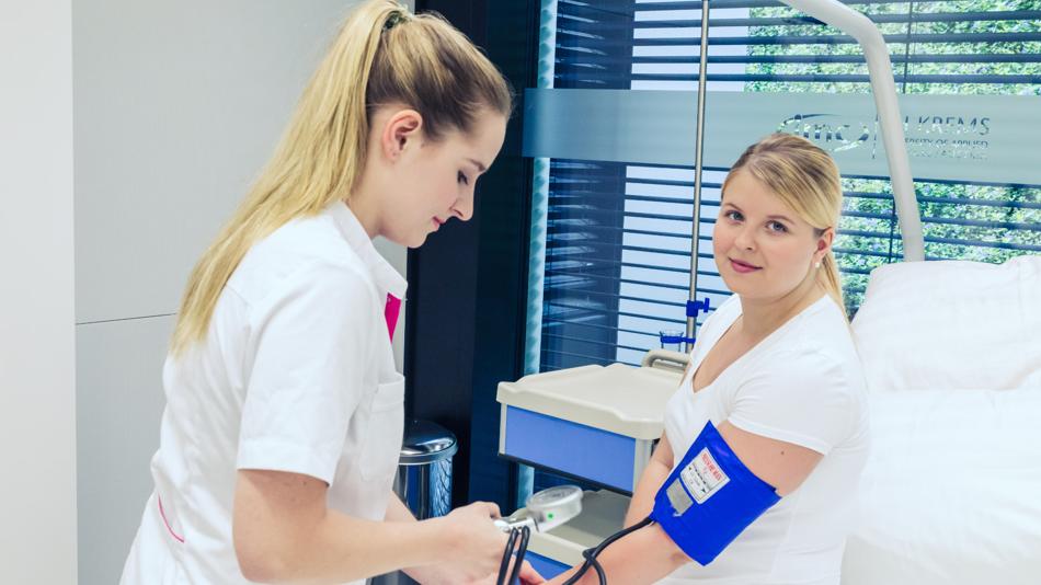 Eine Studentin misst einer anderen Studentin den Blutdruck.