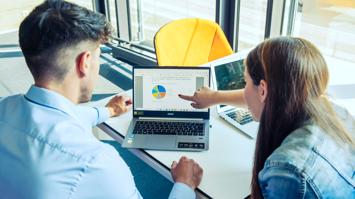 2 Studierende zeigen auf eine Grafik auf einem Laptop.