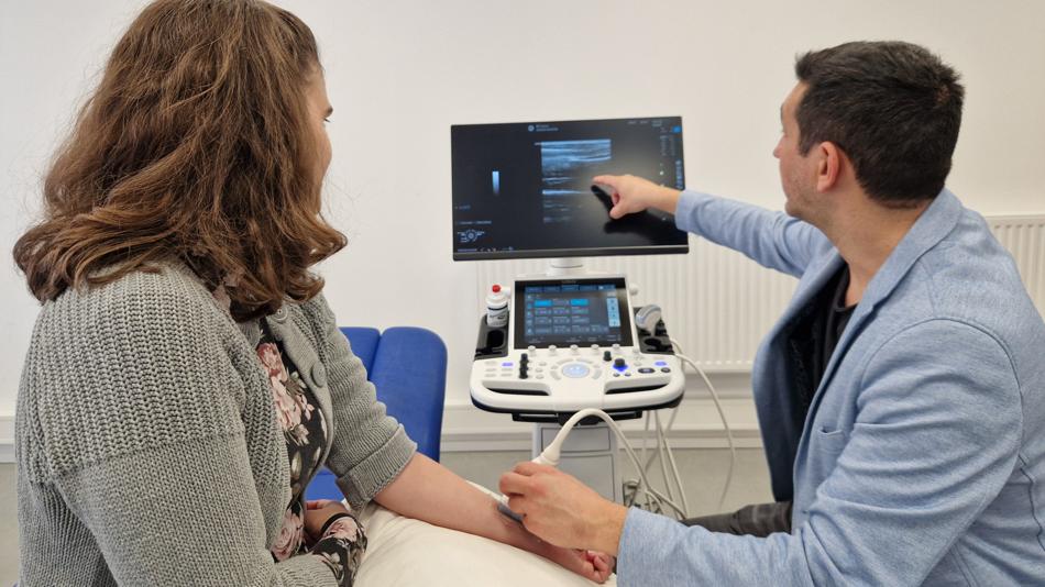 Ein Therapeut macht einen Ultraschall bei einer Patientin.