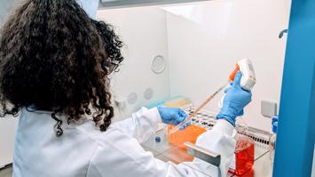 Physikerin im Labormantel beim Pipettieren