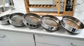 Mehrere Analysensiebe mit getrennten Materialfraktionen auf der Laborbank