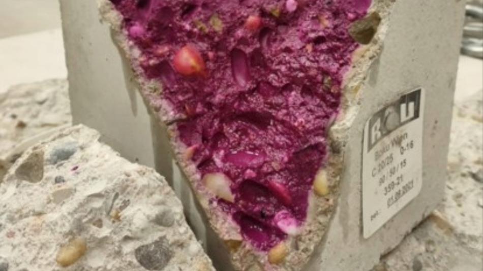 Aufgebrochener Betonwürfel im Labor mit pink gefärbter Bruchfläche zur Sichtbarmachung der Karbonatisierung