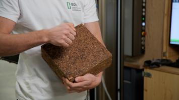 Eine Person hält einen Baustein in der Hand