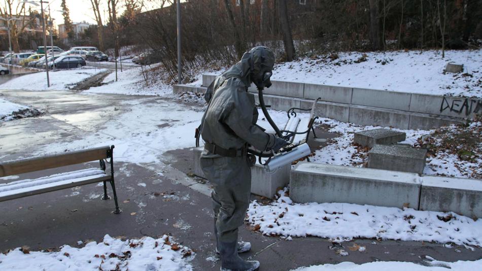 Eine Person im Schutzanzug führt Messungen auf einem winterlichen Gehweg durch