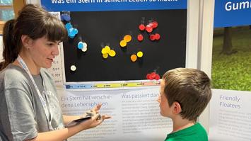 Physikerin erklärt einem jungen Besucher der Langen Nacht der Forschung vor einem Plakat
