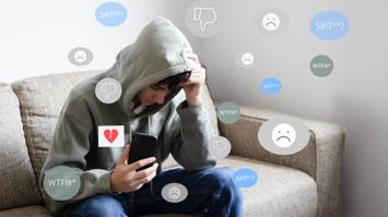 Unglücklicher junger Mensch mit Smartphone in der Hand