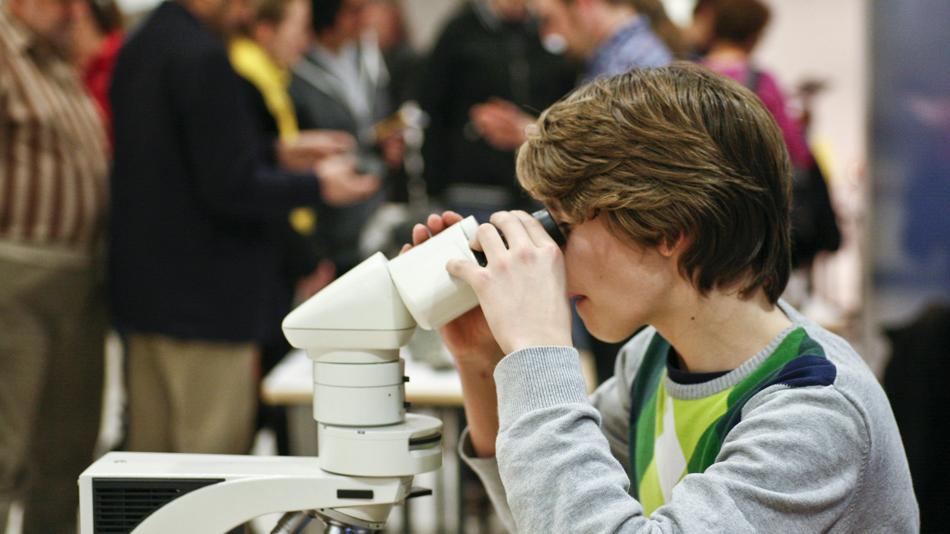 Kind blickt durch ein Mikroskop