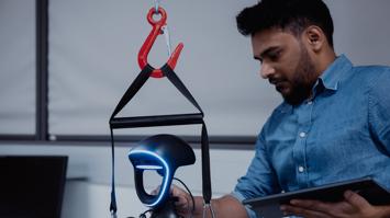 Forscher mit Tablet justiert einen humanoiden Roboter mit blau leuchtendem Gesicht.