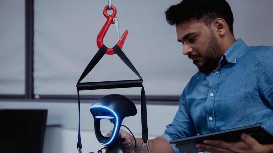 Forscher mit Tablet justiert einen humanoiden Roboter mit blau leuchtendem Gesicht.