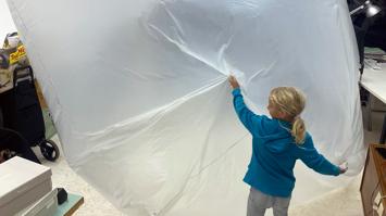 Aufgeblasener, großer Folienwürfel, der von einem Mädchen festgehalten wird.