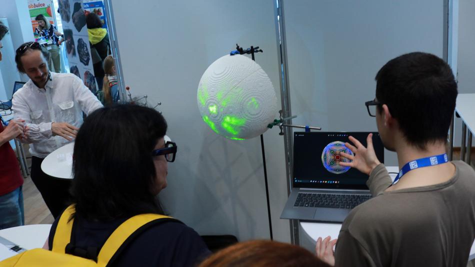 Personen betrachten weiße Halbkugel mit grünen Lichtern