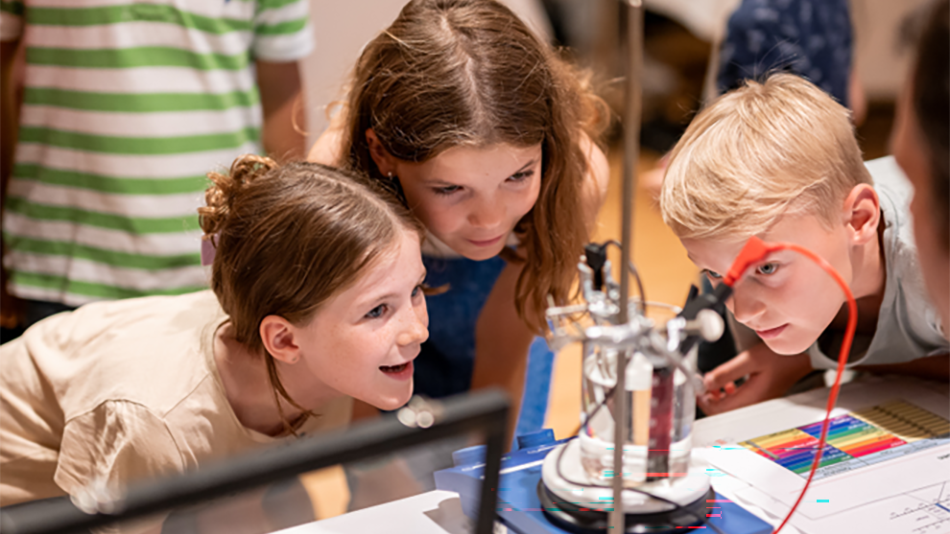 Drei Kinder bestaunen ein Experiment