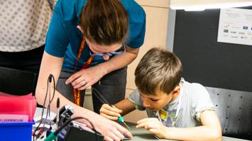 Das Bild zeigt Besucher:innen beim Löten und Basteln bei der Langen Nacht der Forschung