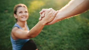 Hand die einer Frau beim aufstehen hilft