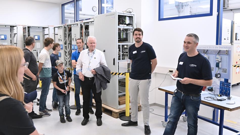 Das Bild zeigt Mitarbeiter:innen von Sprecher Automation und Besucher:innen bei einem Rundgang durch die Fertigung.
