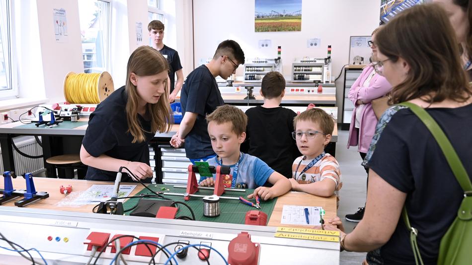 Lehrlinge bei Sprecher Automation beim gemeinsamen Löten mit Kindern in der Lehrwerkstatt.